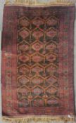 An antique Afhgan Balouch hand knotted wool rug having central design of repeated gul motifs,