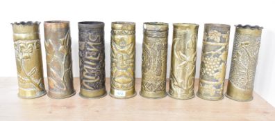 A group of eight German World War I brass trench art shell cases, each embossed and hand hammered