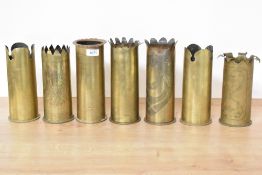A group of seven German World War I brass trench art shell cases, each with engraved decoration