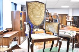 An Edwardian mahogany carver salon chair having later upholstery to shield back, arm supports and