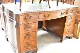 A mid to late 20th Century reproduction mahogany pedestal desk having shaped skiver top , with