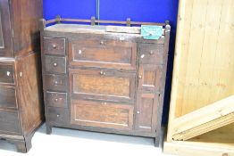 An Arts & Crafts oak side/workshop cabinet with galleried back , three central drop flaps , with