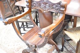 A traditional Oriental style savanorola chair having carved dragon arms and Green man/foliate head