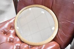 A reproduction gilt framed and bevelled oval wall mirror, of Regency design with bead, reeded and