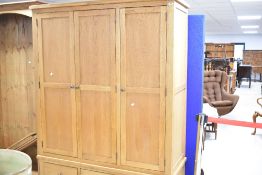 A modern golden oak triple wardrobe , having triple drawer base, dimensions approx. H192 W146 D57cm