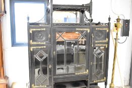 A late Victorian ebonised display cabinet in the Aesthetic style, having elaborate brass hinges,
