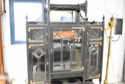 A late Victorian ebonised display cabinet in the Aesthetic style, having elaborate brass hinges,