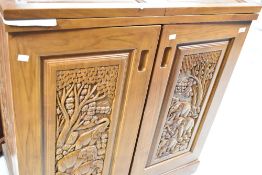 An Oriental hardwood drink cabinet/bar, having extensive carving throughout and fitted interior,