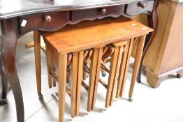 A vintage part teak nest of four slim tables, nesting under larger table with castors (62 x 42cm)