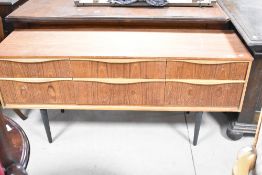 A vintage teak sideboard having six drawer arrangement on tapered legs, having been painted and