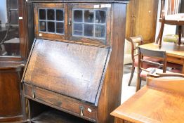 An early 20th Century oak bureau having display upper section with leaded glass doors over drop flap
