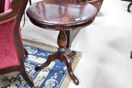A reproduction dark stained pedestal table having circular top on turned column and triple splay