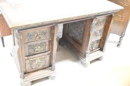 A late 19th or early 20th Century oak pedestal desk, having carved drawer fronts with brass ring