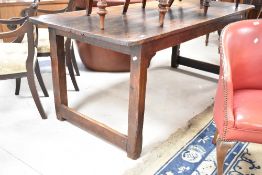A 19th Century pine kitchen refectory style table of plank top construction, in a dark stain