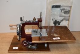 A vintage Essex Engineering Works miniature hand crank sewing machine, having a small wooden
