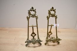 Two 20th-century brass display stands/easels, featuring ornate foliate and scrollwork detailing,
