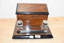 A late 19th to early 20th-century ebonised desktop writing cabinet, with inkwells, featuring a