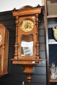 A 19th-century Vienna-style wall clock, featuring a carved wooden case, ornately turned columns