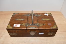 An early 20th-century oak and brass cigar case, having decorative brass mounts, a central handle,