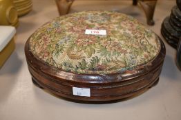 A small early to mid 20th-century tapestry foot stool, featuring a floral cushion upon three ball-