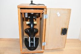 A 20th-century metal microscope in light wood case, having a selection of lenses, 35cm x 22cm box,