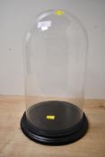 A tall contemporary decorative display dome, having a large glass dome and black resin base,