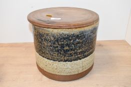 A large 20th-century studio pottery container, having a turned wooden lid and two tone drip glaze