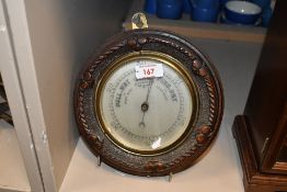 A late 19th-century English aneroid barometer in a carved wooden case, featuring an ornate, rope
