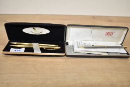A boxed pencil in brushed steel with gold trim and a boxed Centennial ballpoint pen and pencil set