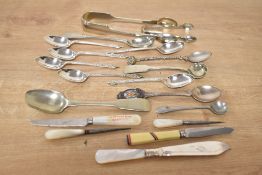 A small collection of flatware including teaspoons, sugar tongs and two fruit knives having mother