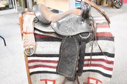 An American style ornate saddle with some tack and stirrups in very good condition and a pine