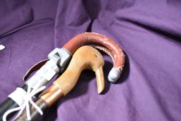 A short hazel walking stick with a carved birds head sold with an ebonised shafted shooting stick