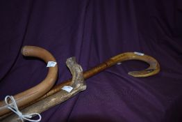 Three sticks one with a sheeps horn crook with a pheasant carved into the tip of the horn