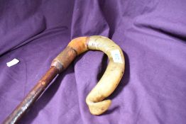 A Shepherds cook style walking stick with the crook made from a blend of rams horn into wood above a