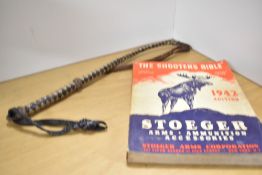 A leather crop or whip along with a 1942 edition of Stoeger catalog 'the shooters bible'