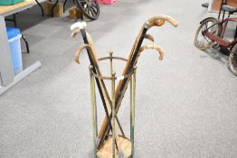 A circular framed copper stick stand containing eight walking sticks