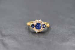 An Edwardian 18ct gold sapphire and diamond ring having a central sapphire, approx 0.5ct flanked