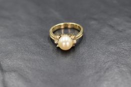 A yellow metal presumed gold pearl and diamond set ring, the central cultured pearl having a cream