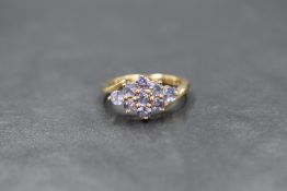 A 9ct gold tanzanite set cluster ring, the nine round cut tanzanites in a lozenge motif with cross