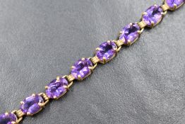 A 10ct gold amethyst set tennis bracelet, the twenty oval cut amethysts in four claw settings,