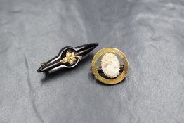 A yellow metal circular cameo brooch, probably gold having a central cameo within an open border,