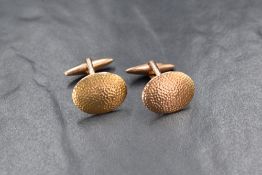 A pair of 9ct gold cufflinks, the oval panels having planished decoration, marked 9ct, 7.6g