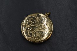 A 9ct gold locket pendant, of circular form having scroll decoration to the front, marked 375, 3cm