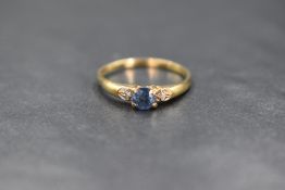 A 9ct gold sapphire and diamond chip ring having a central sapphire in a claw set mount flanked by