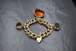 A 9ct gold curb link charm bracelet, having a 9ct heart padlock, 9ct textured ring charm, a 9ct