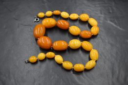 A string of butterscotch amber beads of oval uneven form, measuring between 3.5cm and 1.5cm,