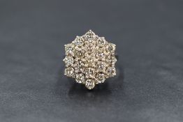 An 18ct white gold diamond set cluster ring, the nineteen round brilliant cut diamonds in a step