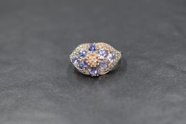 A 14ct gold diamond and possibly tanzanite set ring, the floral motif ring set with diamond chips