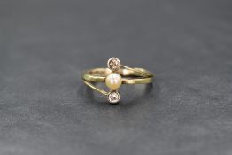 A yellow metal Artisan made seed pearl and diamond ring having a central pearl within crossover