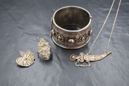 Four pieces of white metal jewellery including a Middle Eastern style hinged bangle with bar